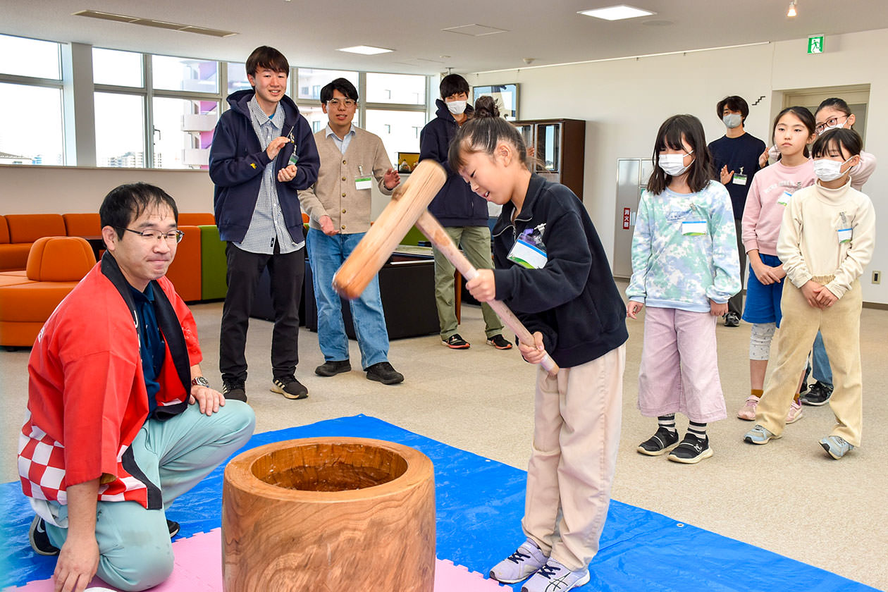 育てたもち米を使って一生懸命餅を付くスクール生の写真